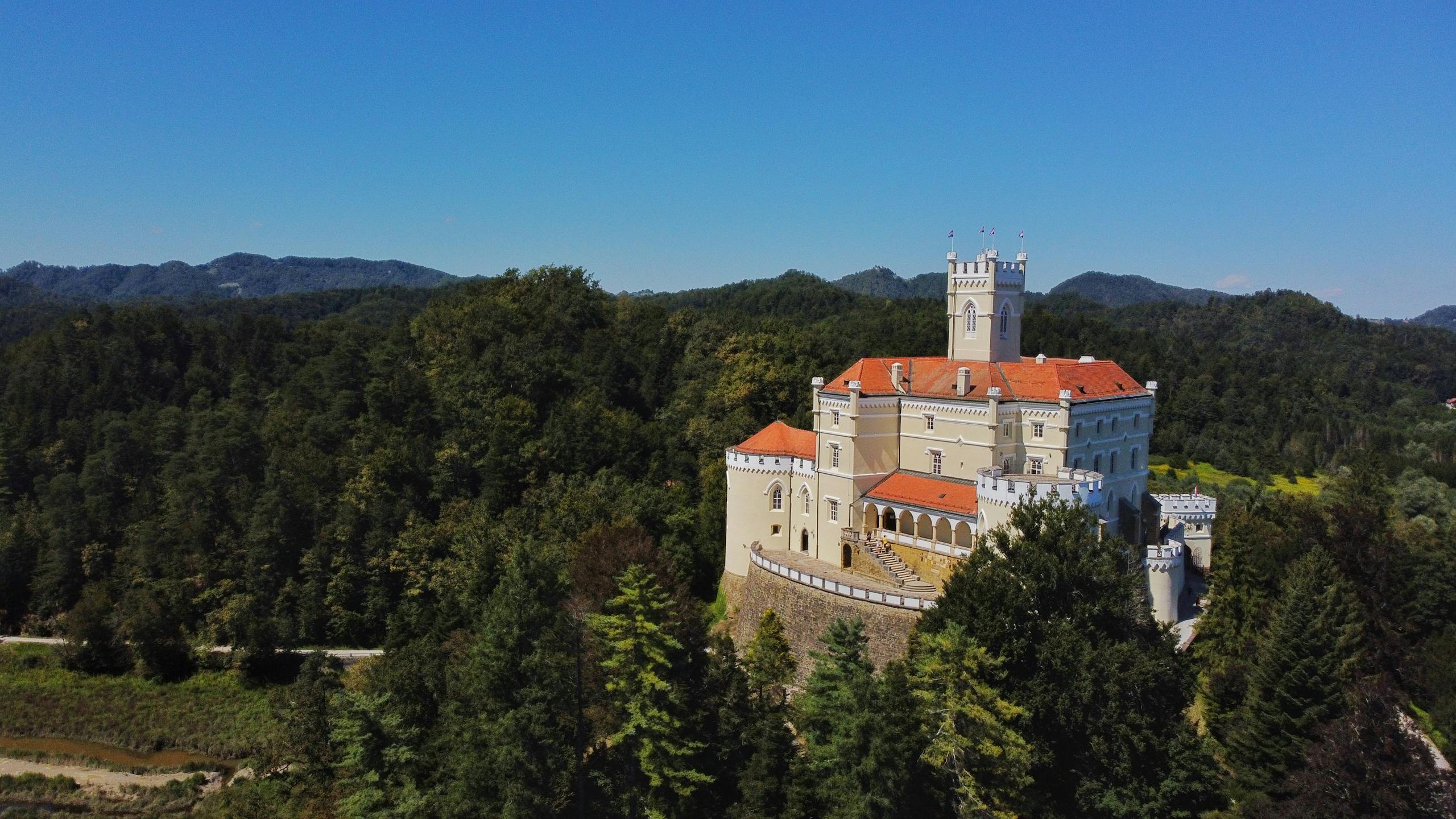 Explore the historic Trakoscan Castle set amid lush greenery and rolling hills, captured from an aerial perspective.